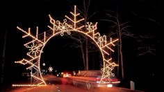 an archway decorated with christmas lights and snowflakes on the side of a road