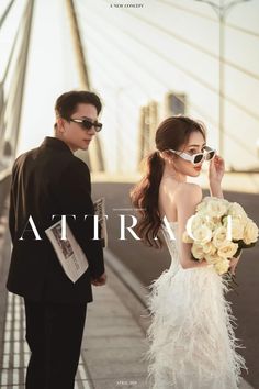 a man and woman standing next to each other in front of a bridge wearing sunglasses