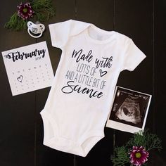 a baby's bodysuit and photo next to flowers