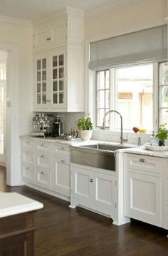 a kitchen with white cabinets and stainless steel sink in the center, along with an open window