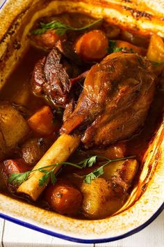 a bowl filled with meat and potatoes on top of a table