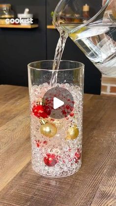 someone pouring water into a glass filled with christmas decorations