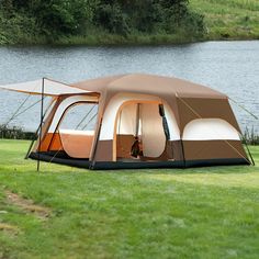 a tent set up on the grass next to a body of water