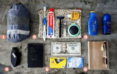 the contents of a travel bag laid out on top of a cement floor next to a wallet