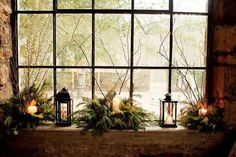 a window sill filled with candles and greenery