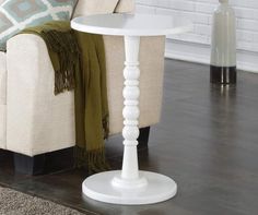 a white table sitting on top of a wooden floor next to a chair and ottoman