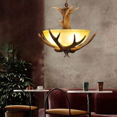 a light fixture hanging from the ceiling in a room with red velvet chairs and tables