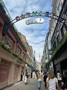 people are walking down the street in front of shops and restaurants on a sunny day