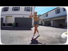 a woman in short shorts and socks standing on a skateboard with her hands up