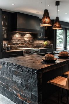 a large kitchen with black cabinets and granite counter tops, along with two hanging lights above the island