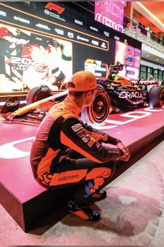 a man sitting on top of a bench next to a racing car in a museum