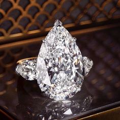 a large diamond ring sitting on top of a black table next to a metal wall