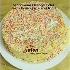 a cake with white frosting and colorful sprinkles on top is sitting on a plate