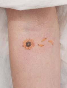 a small sunflower tattoo on the left thigh and right leg, with two petals coming out of it