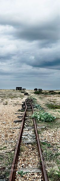 an abandoned train track in the middle of nowhere, under a cloudy sky with dark clouds