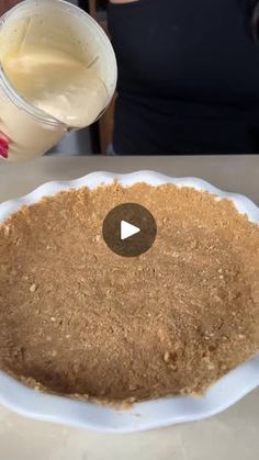 a person pouring milk into a cake on top of a white plate with a cup