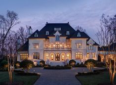 a large white house with lots of windows and lights on it's front porch