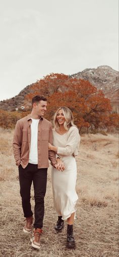 a man and woman holding hands walking through the desert