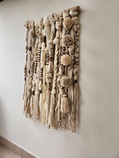 a wall hanging made out of rope and wooden beads on the side of a white wall