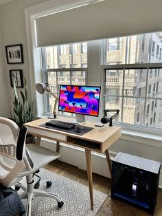 a desk with a computer on it in front of a window overlooking the cityscape