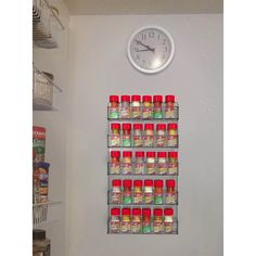 a clock mounted to the side of a wall next to canned food cans and spices