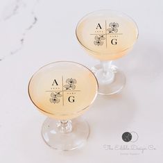 two wine glasses sitting on top of a table with the words ag written in them