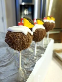 four cake pops with frosting and flowers on them sitting on top of a table