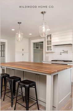 a kitchen island with stools in front of it and the words wildwood home co above it