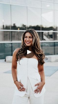 a woman standing in front of a building with her hands on her hips and smiling