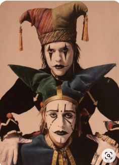 two clowns dressed in costumes and hats, one with his head turned to the side