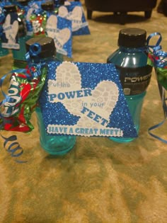 some blue bottles are sitting on a table with ribbon around them and tags in the shape of hearts