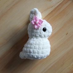 a white crocheted stuffed animal with a pink bow