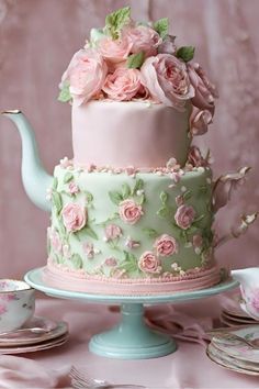 there is a cake with pink flowers on it and a teapot next to it