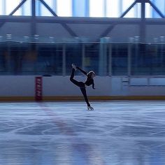 a woman skating on an ice rink with her arms in the air while wearing black