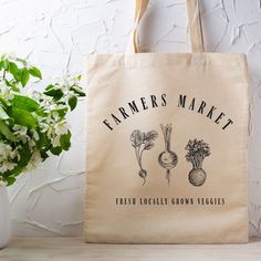 a farmers market bag sitting on top of a table next to a potted plant