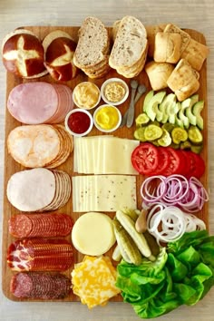 a wooden cutting board topped with lots of different types of cheeses and meats