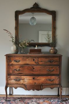 an old dresser with a mirror and vases on top