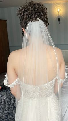 the back of a bride's wedding dress, with her veil draped over her head