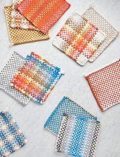 six woven coasters in different colors on a white counter top, each with an orange and blue design