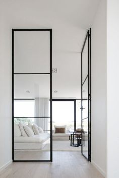 a white room with black framed glass doors and wood flooring is featured in the article, custom wooden doors