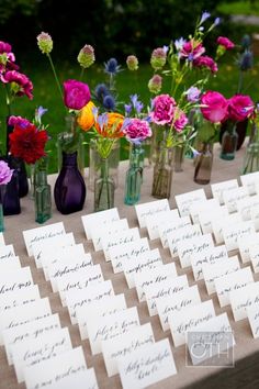 there are many small vases with flowers in them on the table, all lined up