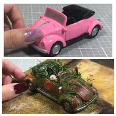 a pink toy car sitting on top of a wooden table next to a hand holding a small model car