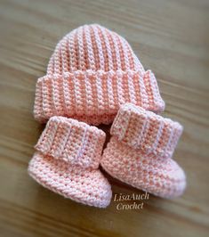 two pink knitted baby booties sitting on top of a wooden table