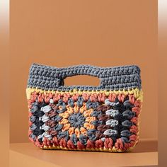 a crocheted purse sitting on top of a table next to a brown wall