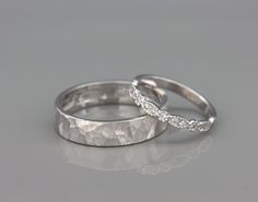 two white gold wedding rings with diamonds on top, one in the shape of a wave