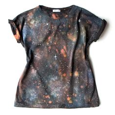 a t - shirt with an image of the stars and planets on it, sitting on top of a white surface