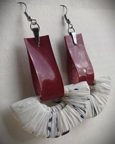 pair of red and white earrings hanging from hooks on the side of a wall with fabric wrapped around them