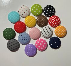 several different colored polka dot buttons on a white surface with one button facing the camera