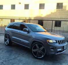 a grey jeep parked in front of a fence