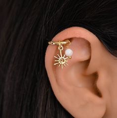 a woman's ear is adorned with a gold plated sun and pearl